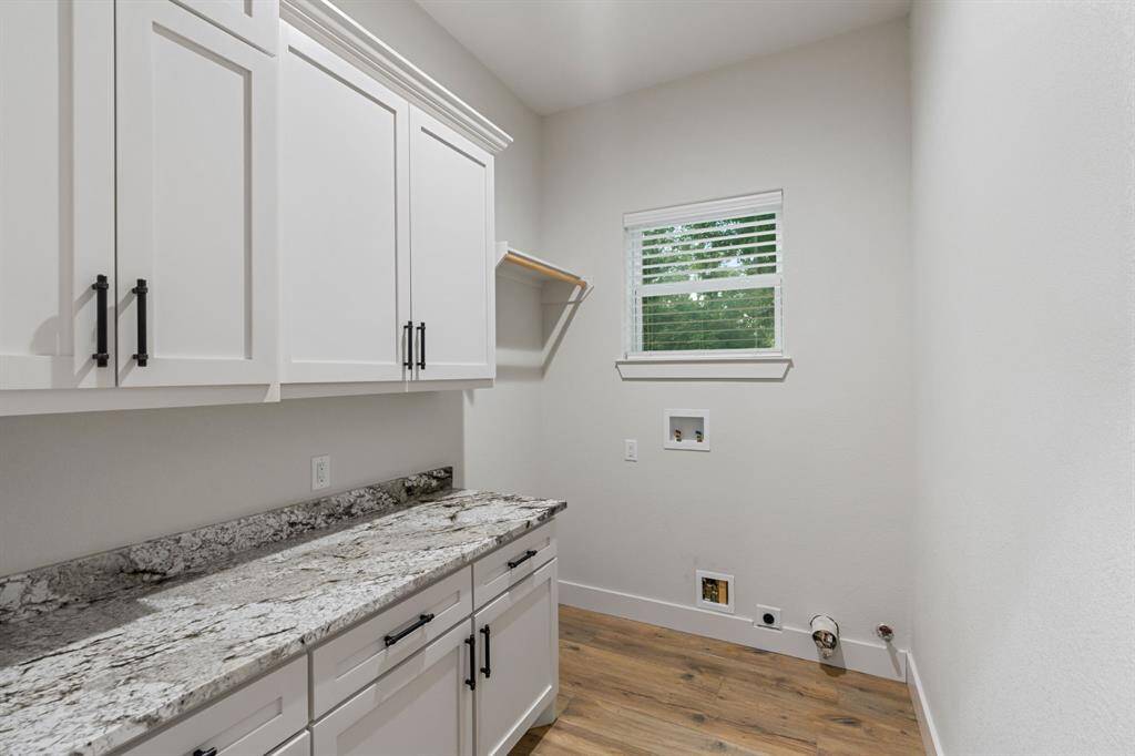 The laundry room behind a sliding barn door features granite counters, cabinets, and washer/dryer connections.