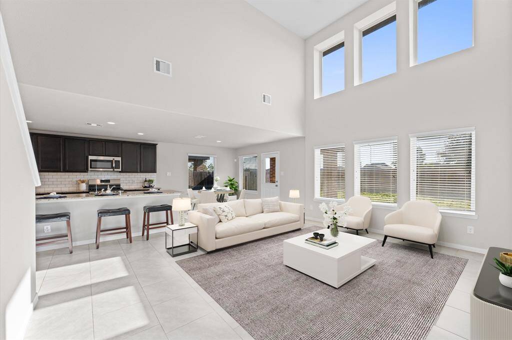 The living room is bright and welcoming, with large windows that fill the space with natural light and offer serene views of the backyard.