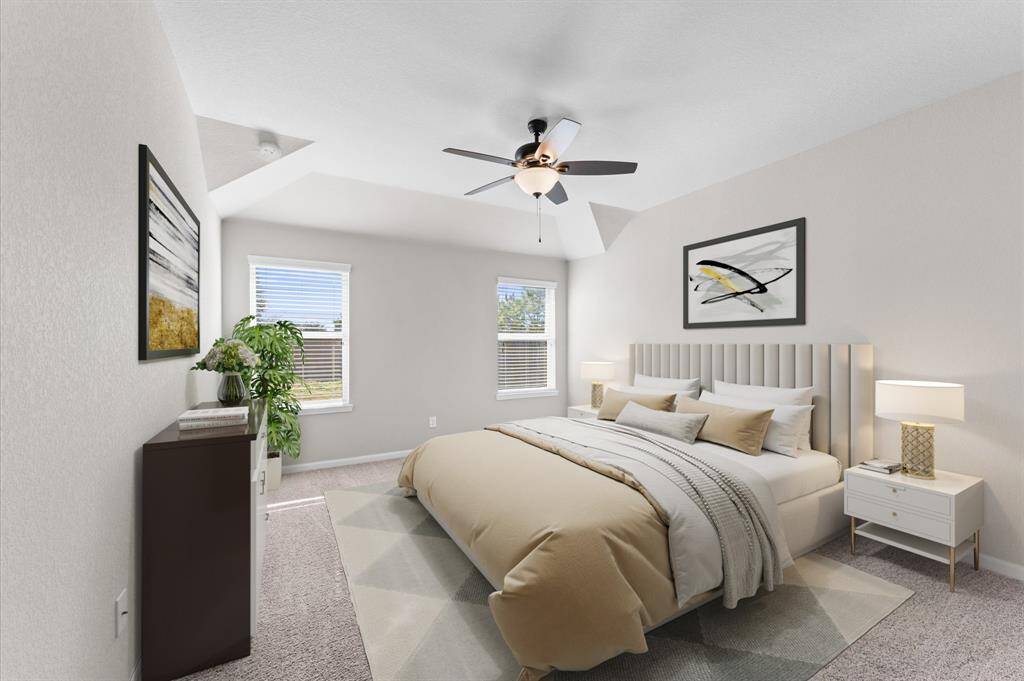 The master bedroom on the first floor offers a peaceful escape with its wide window, ceiling fan, and plush carpet flooring.