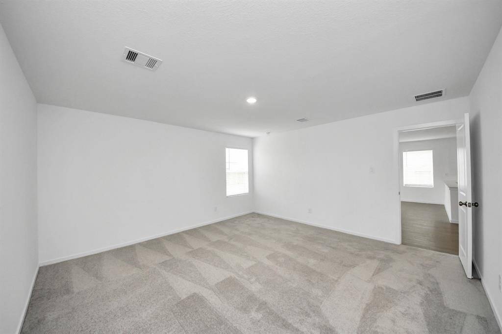 The spacious primary bedroom offers a serene retreat, featuring light walls that enhance the open and airy feel of the space.