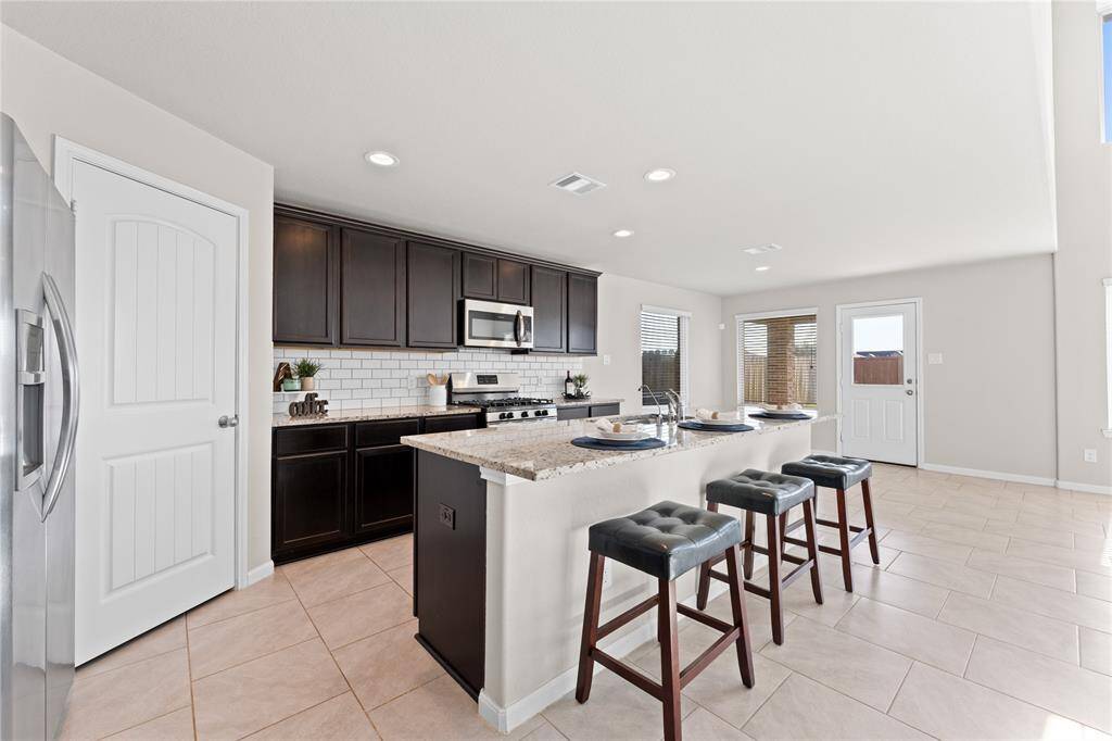 A chef’s dream, the kitchen boasts a large granite island countertop that doubles as a prep area and breakfast bar.