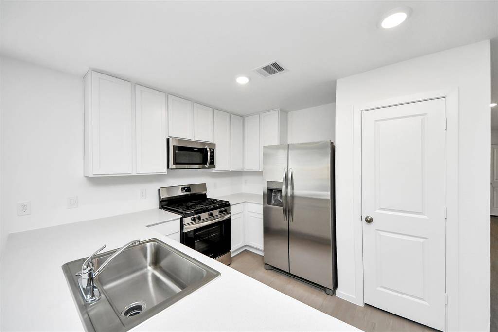 A large island with bar seating invites conversation, while recessed lighting and natural light from the adjoining living space enhance the warm and inviting atmosphere.