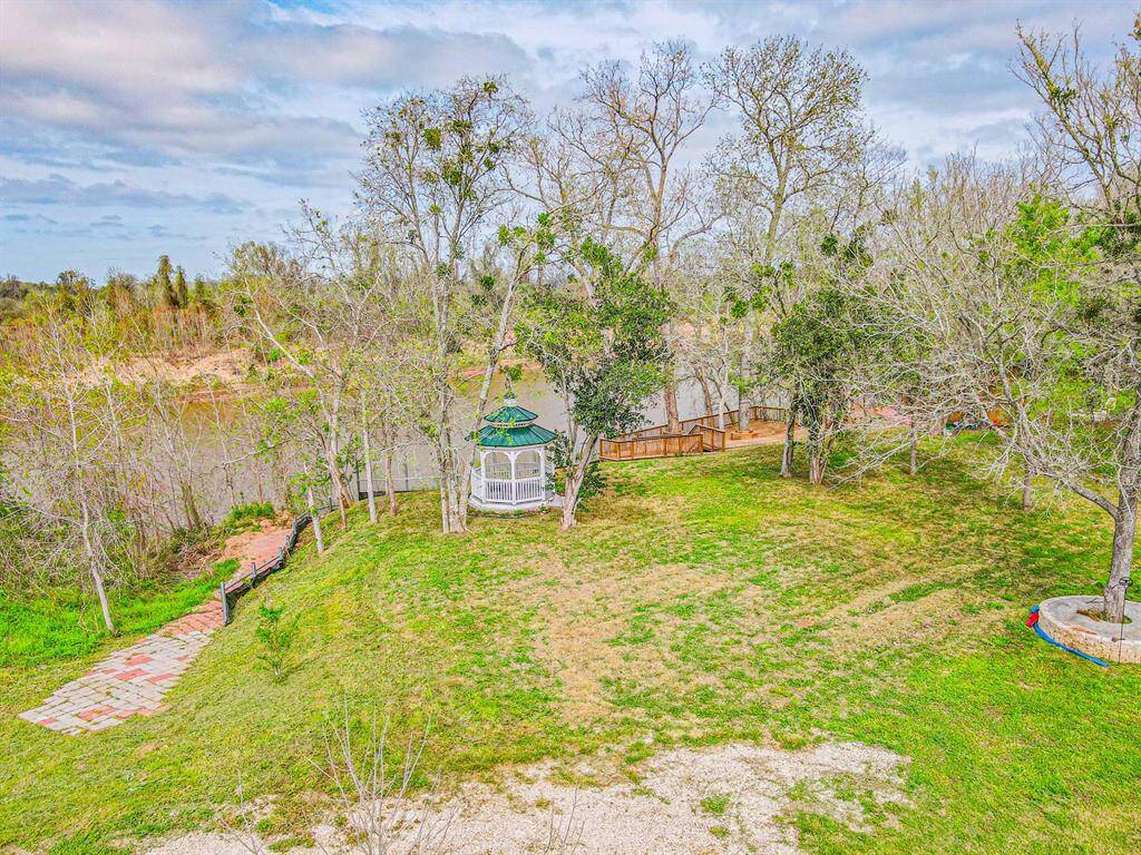Charming outdoor space featuring a scenic view with a gazebo nestled among mature trees, overlooking a serene river. Ideal for relaxation and enjoying nature.