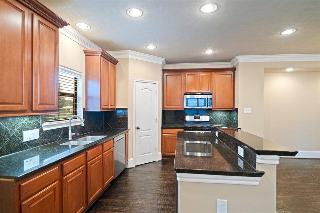 Experience the elegance of this well-appointed kitchen, featuring rich cherry cabinetry, sleek granite countertops, and modern stainless-steel appliances.