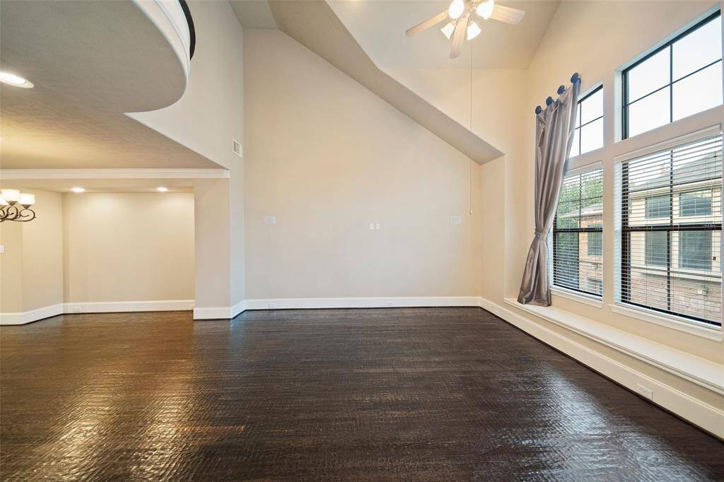 Experience the expansive elegance of this bright living space, boasting high ceilings and large windows that invite natural light to dance across the rich hardwood floors.