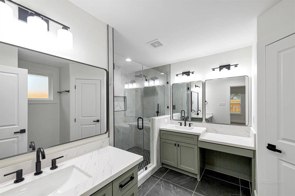 A fully remodeled en-suite with a sleek glass shower, modern fixtures, and elegant quartz countertops.
