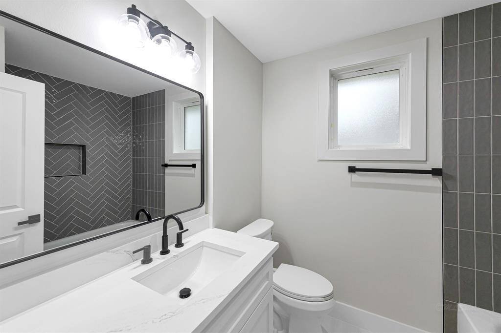 A fully updated bathroom with contemporary fixtures, quartz countertops, and a sleek tile design.