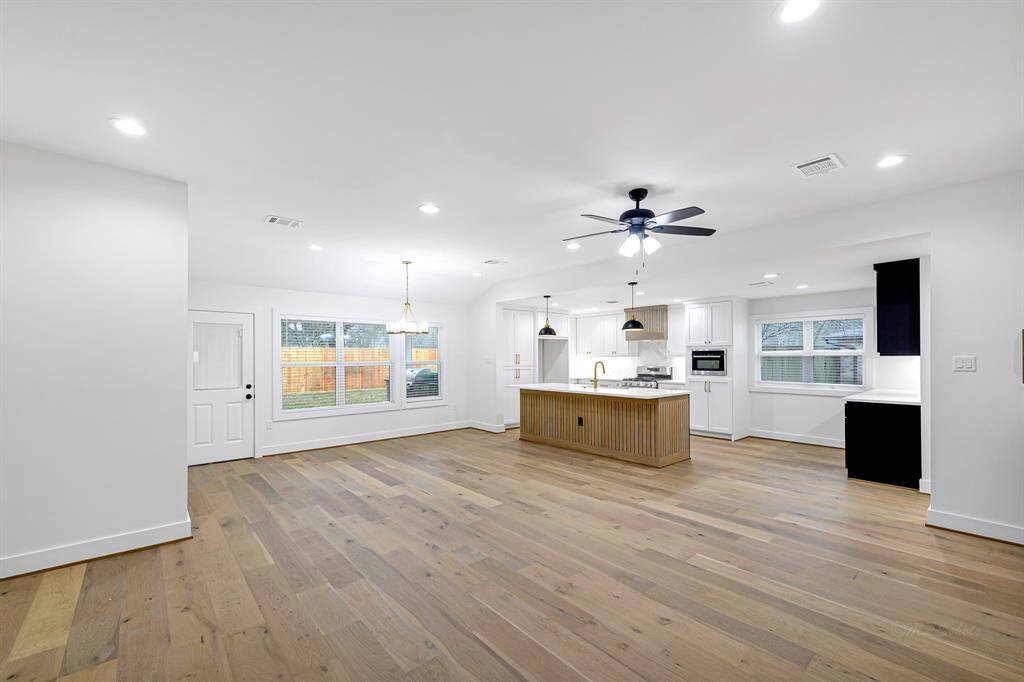 Natural light floods the open-concept living room, highlighting the gorgeous white oak flooring.