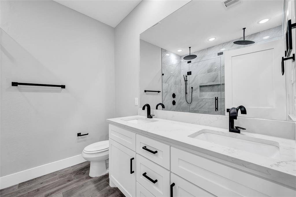 Primary bath features dual sinks and large walk-in shower with dual rain head shower heads as well as a handheld shower head.