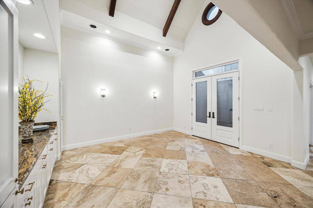 FORMAL DINING ROOM… Features include vaulted and beamed ceiling, French doors leading out to private courtyard, custom built-in cabinetry, buffet with granite counter and wall sconces. Chandelier mount is out of view, but is centered on the vaulted ceiling.