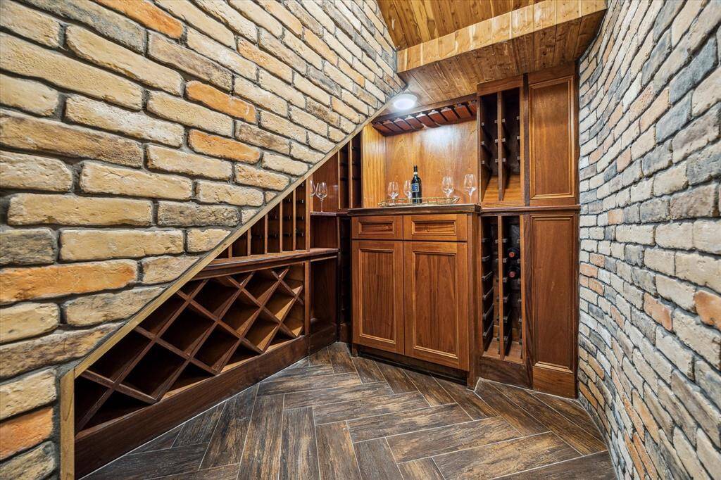 WINE CELLAR… Climate controlled cedar and brick 100+ bottle wine cellar. Custom wood-work includes stemware hanging racks and drawers for wine accessories or cigars.