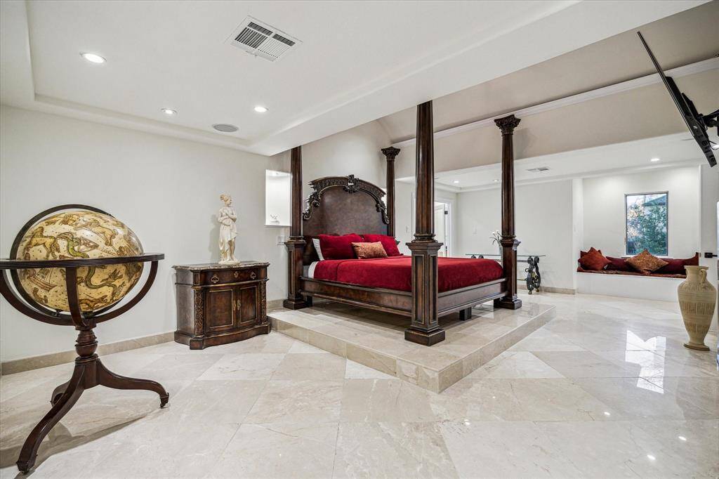 PRIVATE PRIMARY RETREAT… Located on the second floor, the impressive primary suite features marble floors, rotunda ceiling, a gas log fireplace and a custom raised platform space for the king-sized bed. Across the bedroom, the cozy reading nook can be seen next to a large window for natural light.