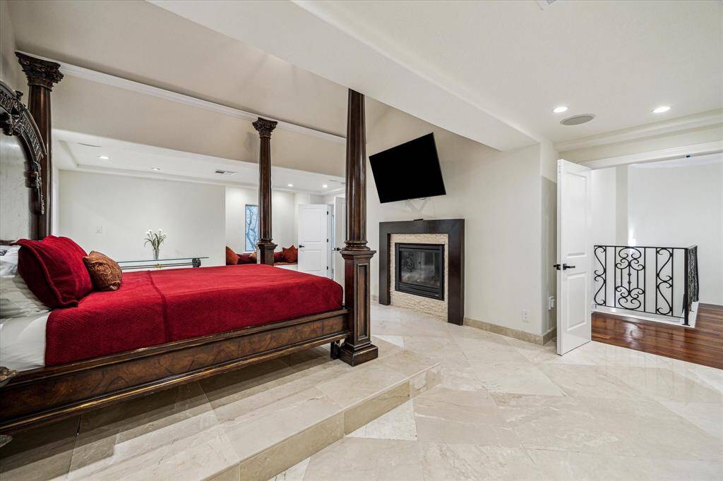 PRIMARY RETREAT… An additional view of this majestic suite shows the double door entry off the stairs.  A gas log fireplace with a 60” adjustable TV mounted above makes for cozy watching from bed.