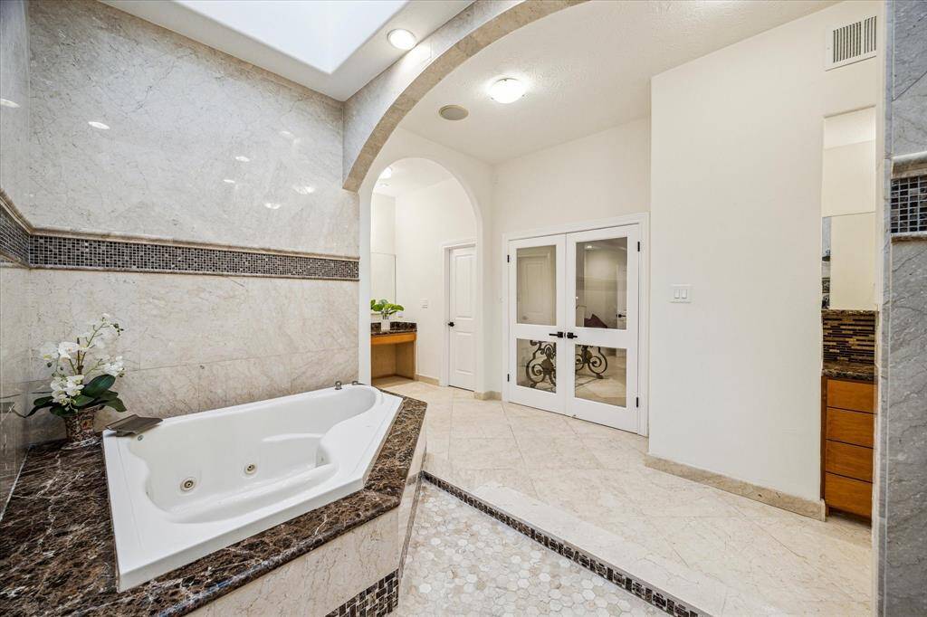 PRIMARY BATHROOM… Imagine soaking in this two-person jetted tub and allowing yourself to simply relax, especially when the marble glows around you in the moonlight.  Note the beautiful granite surround and decorative tile inlay.