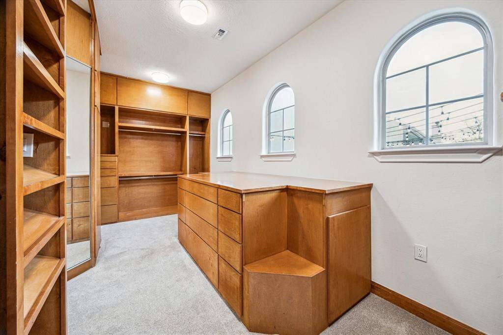 PRIMARY WALK-IN CLOSET… Custom floor to ceiling built-in shelving, drawers, hanging racks and cabinetry.  Three large windows allow an abundance of natural light. Use the three-way mirror to view all angles. A large packing island doubles as further storage.