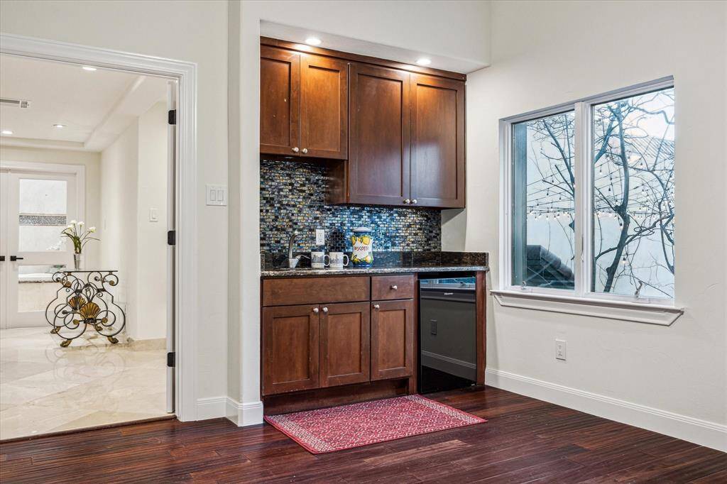 PRIMARY SUITE SITTING ROOM OR STUDY… This view of this room shows the custom cabinetry, granite counters, decorative tile backsplash, undermount sink and Hisense mini-refrigerator. Perfect for waking up and making coffee before making a morning appearance to the rest of the household.