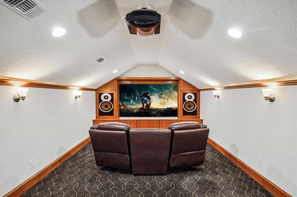 MEDIA ROOM… Dramatic wood stairs lead up to the generously sized media room.  Features include custom carpeting, vaulted ceiling, custom cabinetry, movie screen and projector. Cove lighting, wall sconces, and recessed lighting giving many lighting/dimming options for this space.
