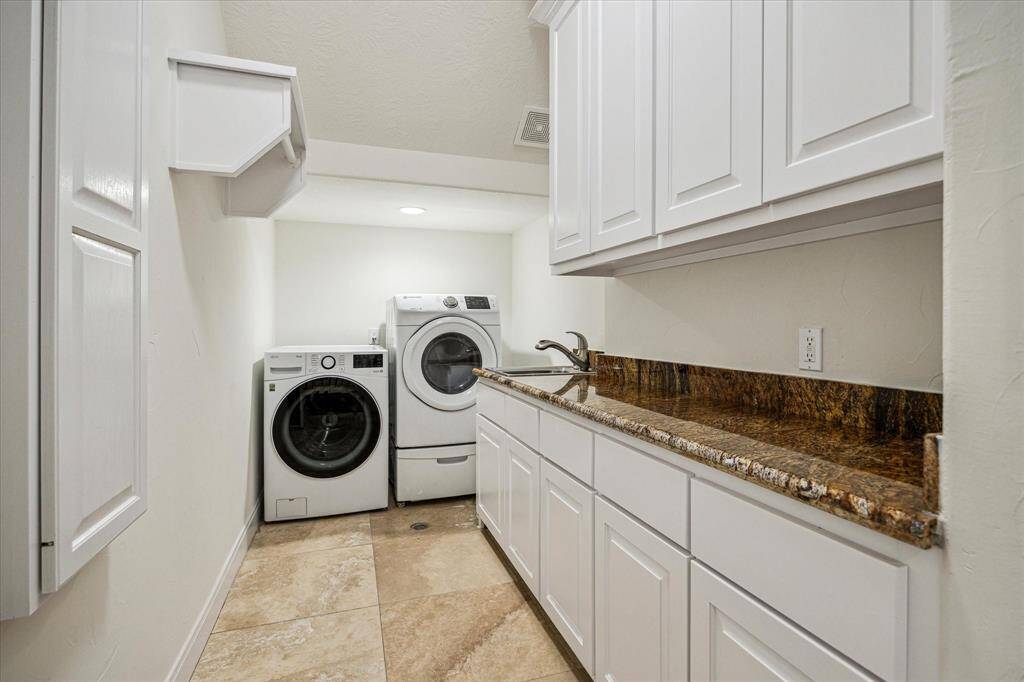 LAUNDRY ROOM… Travertine flooring, granite counter and backsplash, abundant custom cabinetry, stainless utility sink, built-in ironing board and hanging rack, generous counter space for folding, Samsung Moisture Service full sized washer, LG full size Thin Q dryer.