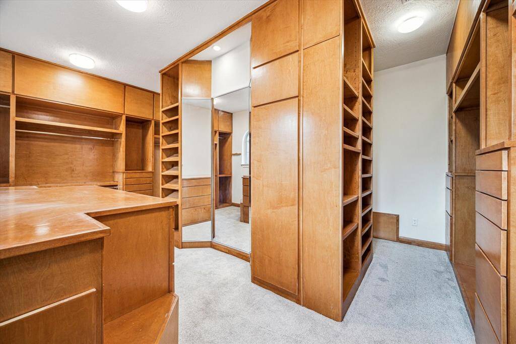 PRIMARY WALK-IN CLOSET… The view of this area reflects the spaciousness, ample storage and shows the three-way mirror.