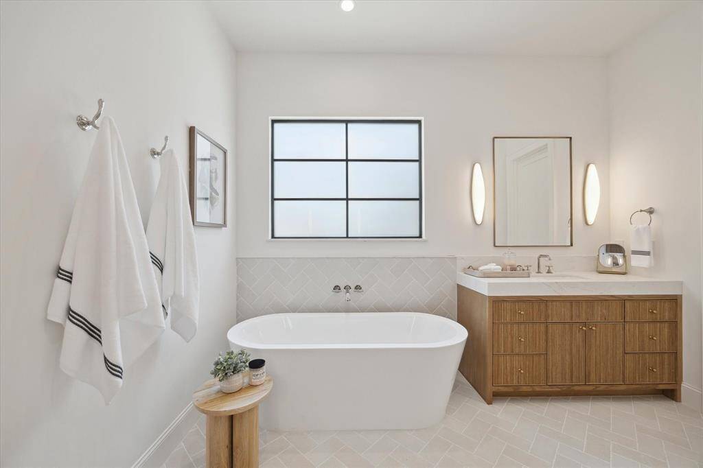 The Primary Bathroom offers double vanities with light sconces from VC by Aerin, Brizo pllumbing fixtures, and white oak cabinetry with quartz countertops.
