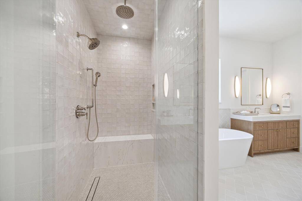 The primary shower with two shower heads plus handheld features tile form Ann Sacks.