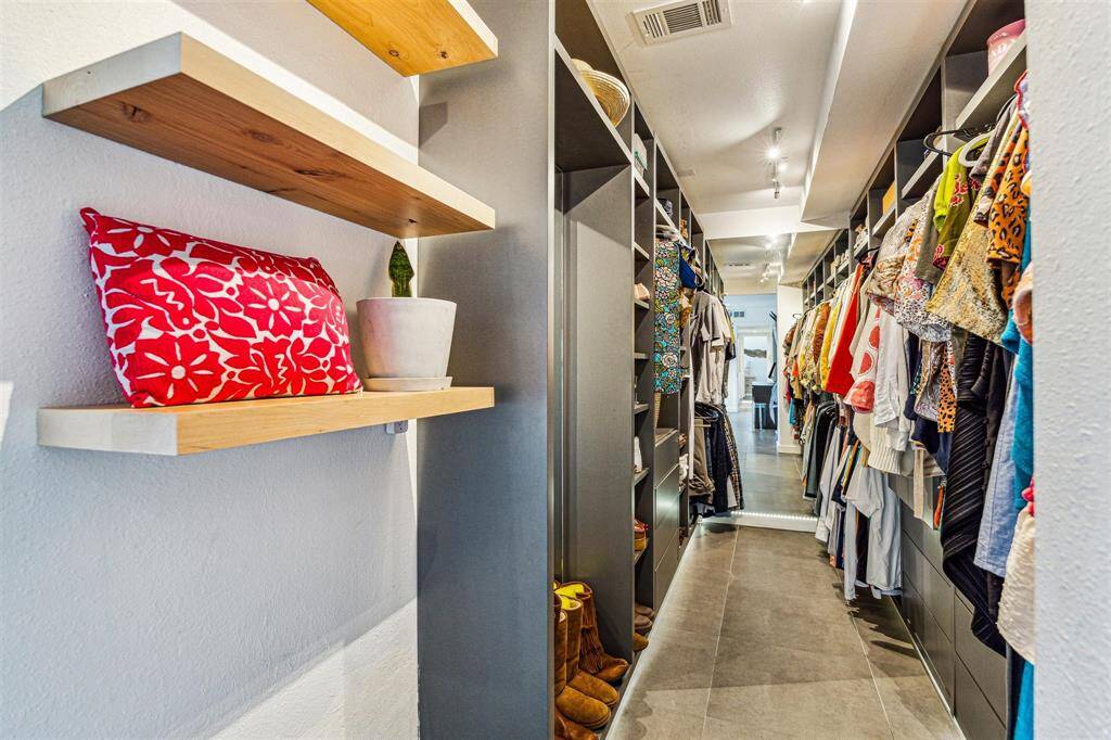 This oversized walk-in closet features custom shelving and built-ins and a secret safe room.