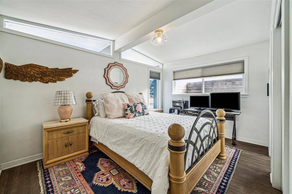 This guest bedroom is located off the front of the home and features an ensuite half bath, vaulted ceilings, designer chandelier, and hardwood floors.