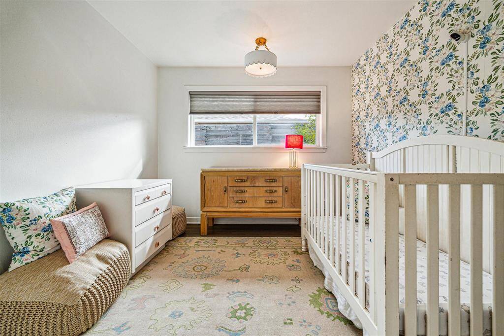 Second guest bedroom in the main house with designer chandelier, hardwood floors, and accent wall with designer wallpaper.