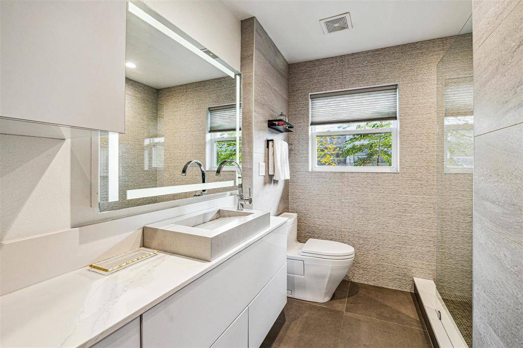 The guest bath includes large vanity with lighted vanity mirror, and walk-in shower.
