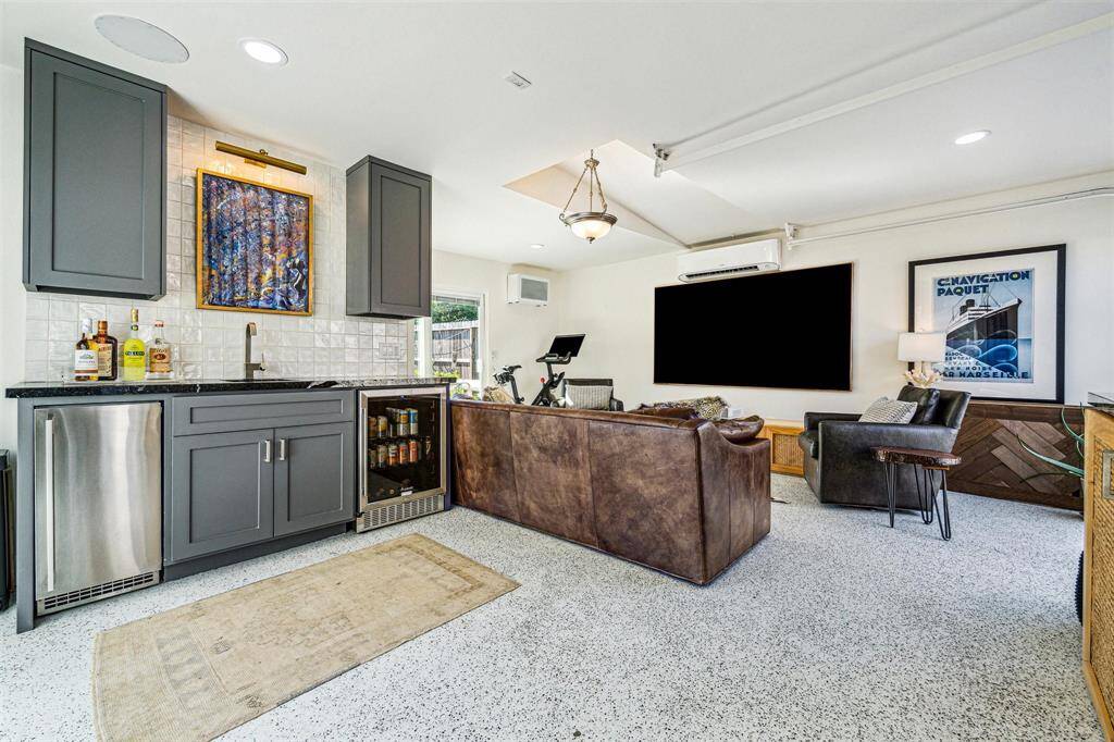 A detached guest suite (380 SF +/-) features two sliding glass doors, roll up glass panel door, epoxy flooring, 2-ton Daikin split HVAC, full bath, and wet bar.
