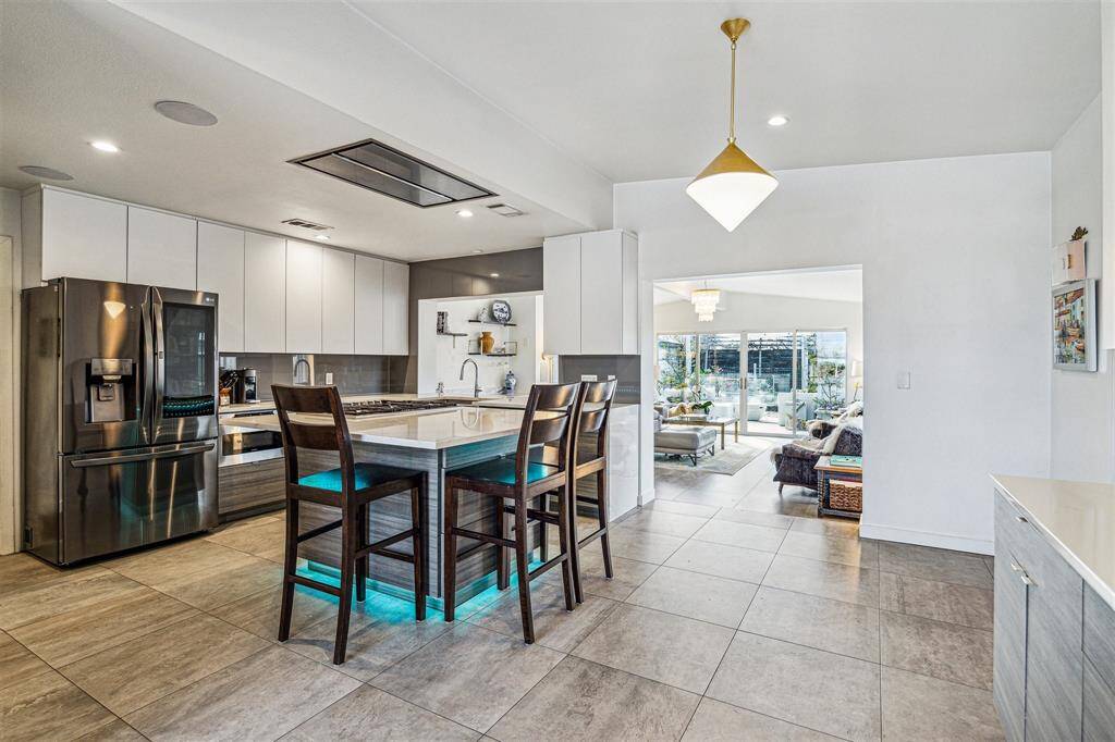 The kitchen is a chef’s dream with oversized island, custom laminate cabinets, quartz counters and backsplash, walk-in pantry, stainless steel appliances, and a custom-built buffet/serving area.