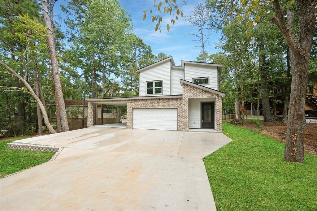 Modern two-story home with a spacious driveway and attached two-car garage, nestled among mature trees in a tranquil neighborhood.