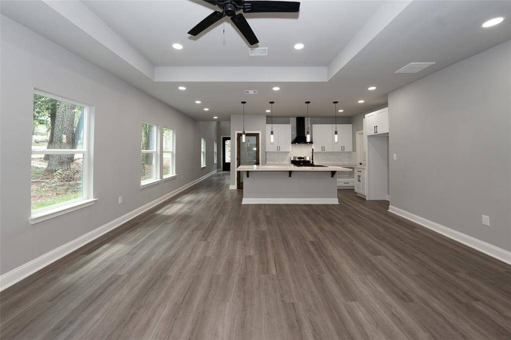 This open-concept living room is bright and spacious, with plenty of windows that bring in an abundance of natural light. Its expansive layout seamlessly connects to the dining and kitchen areas, creating a perfect flow for both relaxation and entertaining. With its inviting design, this living room is a comfortable space where you can enjoy everyday living.