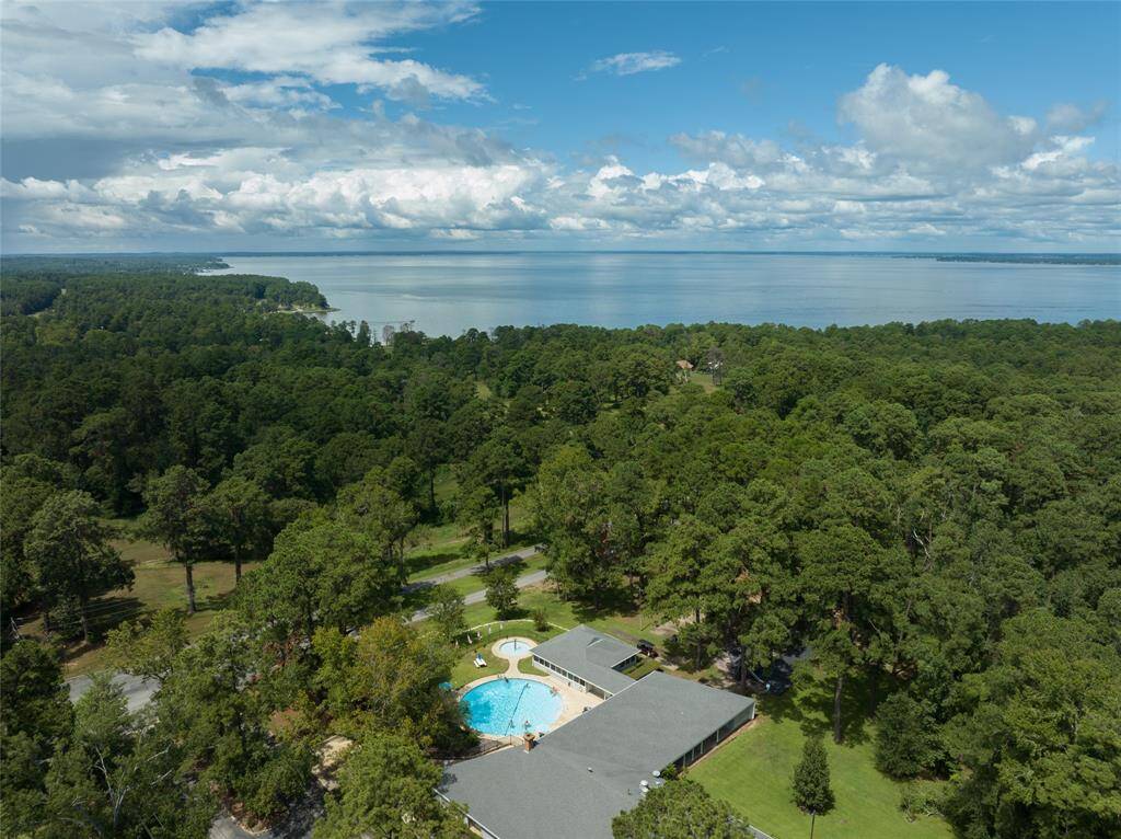 This aerial view showcases the community pool, nestled within a beautifully landscaped area. Surrounded by lush greenery, it offers a peaceful and inviting space to relax, swim, and enjoy sunny days in a tranquil setting. Perfect for both socializing and unwinding, this pool is a true highlight of the community.