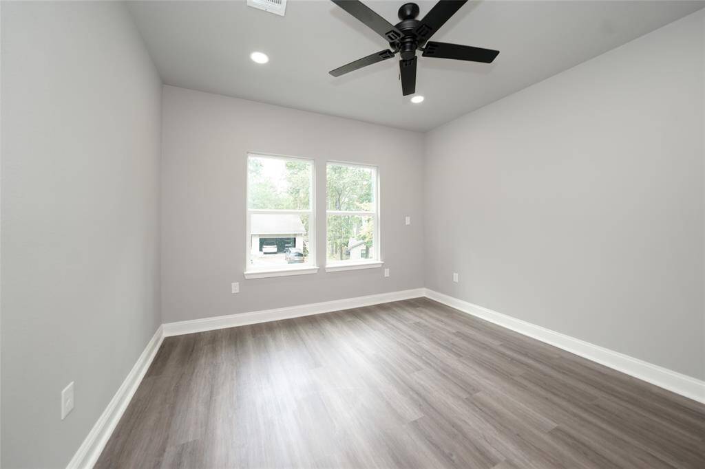 This cozy bedroom is nestled within a modern two-story home, offering a warm and inviting retreat. Surrounded by natural wooded beauty, it provides a sense of tranquility and privacy, perfect for unwinding in comfort.