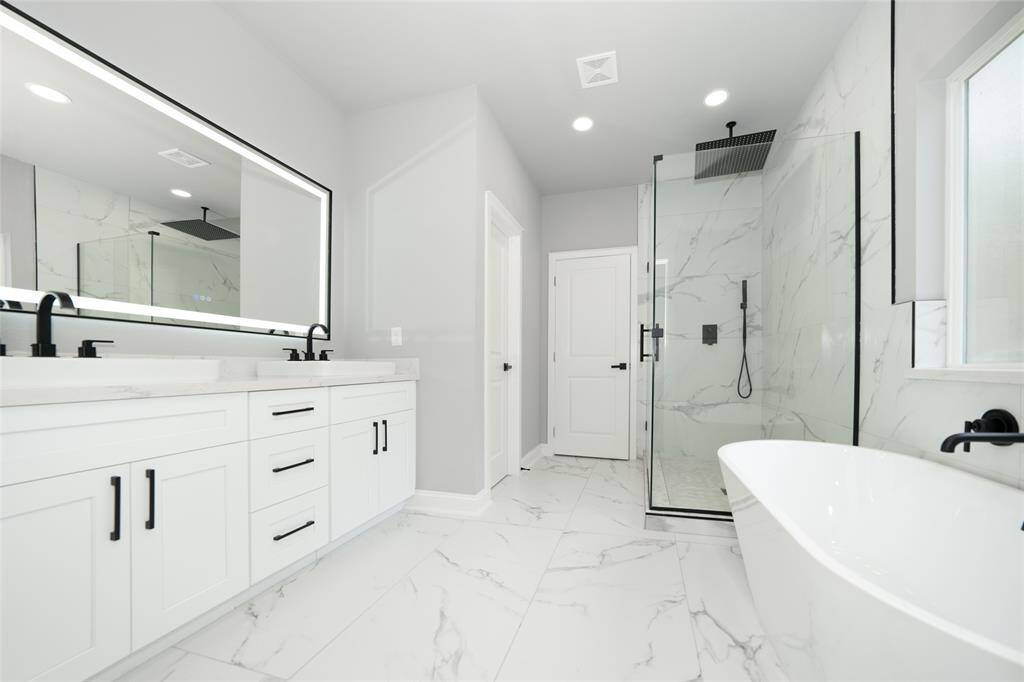 Step into this stunning bathroom, designed to be your personal retreat. It features a luxurious, large bathtub, perfect for soaking away the day, along with a spacious shower for a refreshing start to your morning. A sleek, modern mirror spans the double-sink vanity, offering both style and functionality. With its elegant finishes and thoughtful design, this serene space invites you to relax and feel at home every day.
