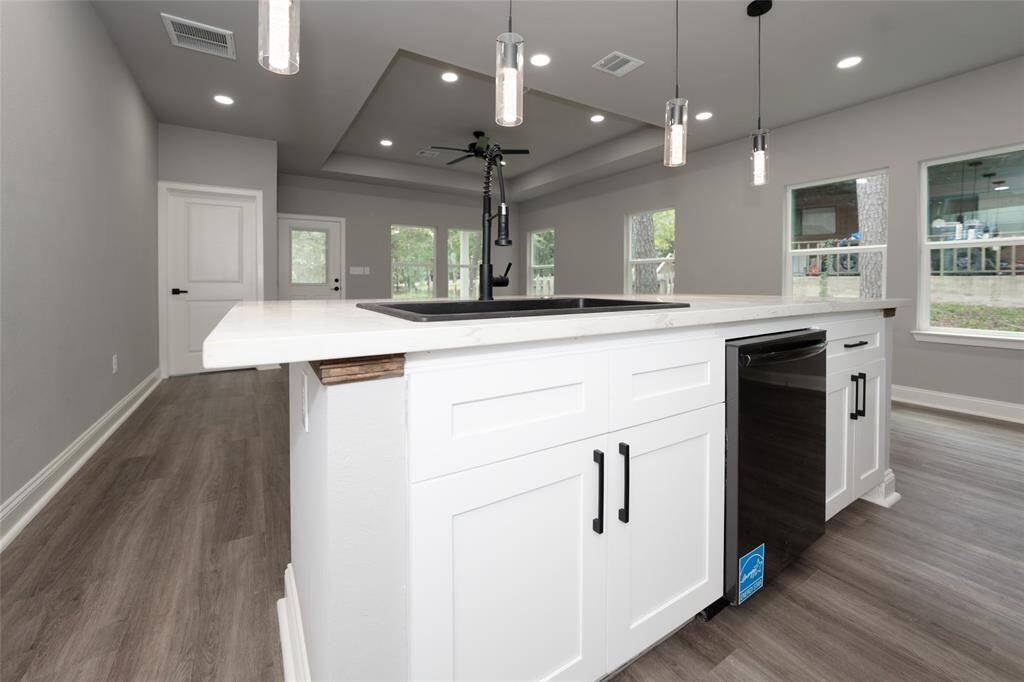 This room is filled with natural light thanks to large windows that create a bright and airy atmosphere. The dark wood flooring adds warmth, while recessed lighting and a ceiling fan provide comfort. The touchless kitchen faucet is a standout feature, combining sleek, modern design with ultimate convenience, making daily tasks effortless. With its blend of style and functionality, this space is perfect for comfortable, everyday living.