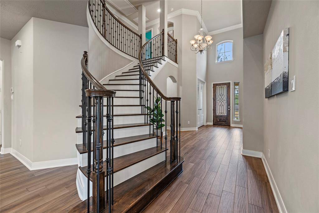 Grand entryway featuring a beautiful staircase with elegant wrought iron spindles, setting the tone for this home's sophisticated design.
