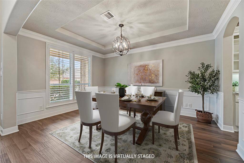 Stunning formal dining room showcasing crown molding, elegant wainscoting, and a beautiful chandelier, adding timeless charm and sophistication.