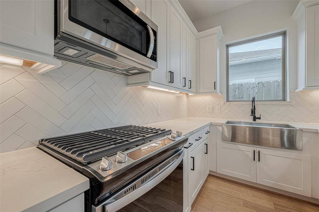 Gas stove, built in microwave and farmhouse apron style stainless sink.