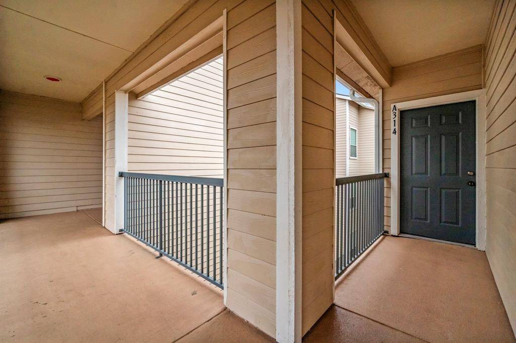 This photo shows a corner entryway to the unit, open railings, and a covered walkway.