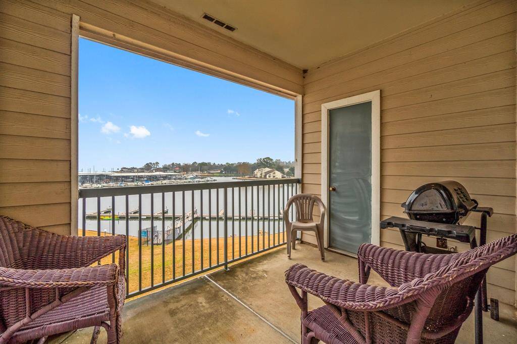 This cozy balcony offers a relaxing view of the marina, perfect for enjoying outdoor moments. It features wicker chairs, a barbecue grill, and a peaceful waterfront setting.
