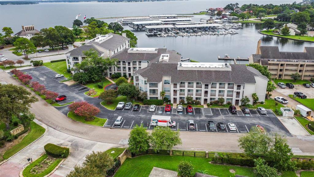 waterfront property with a modern apartment complex surrounded by lush landscaping. It features ample parking, a marina with boat docks, and scenic views of the water, offering a relaxing and convenient lifestyle.