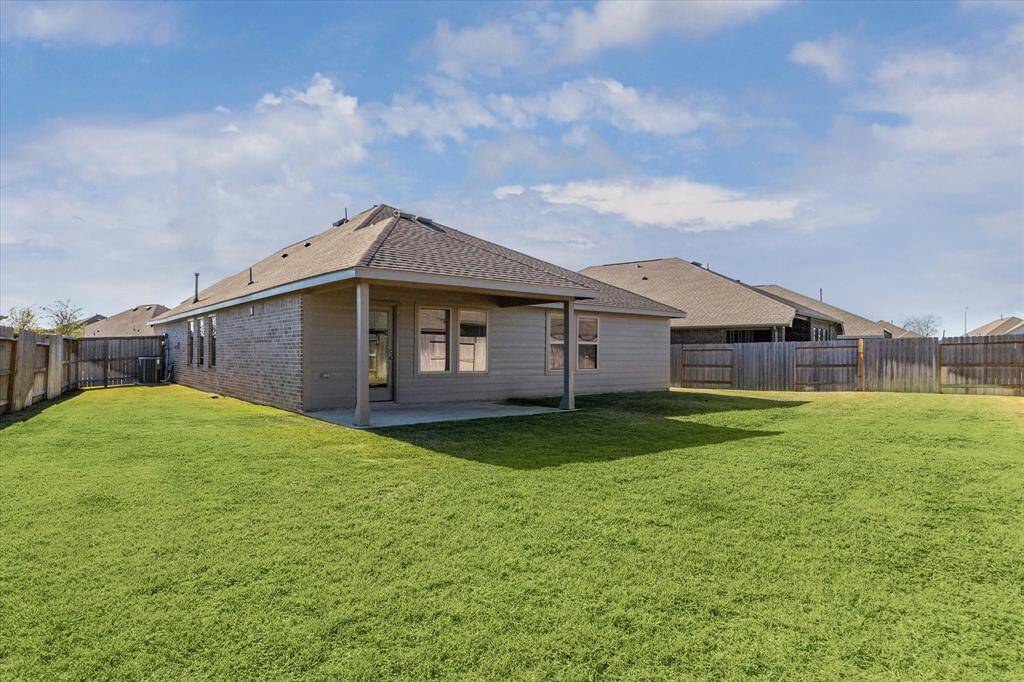 This photo shows the covered patio and the spacious, well-maintained backyard. Ideal for outdoor activities and relaxation.