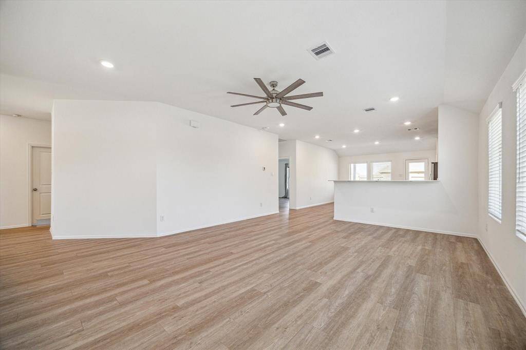 This spacious, open-plan living area features modern wood flooring, neutral walls, and abundant natural light.