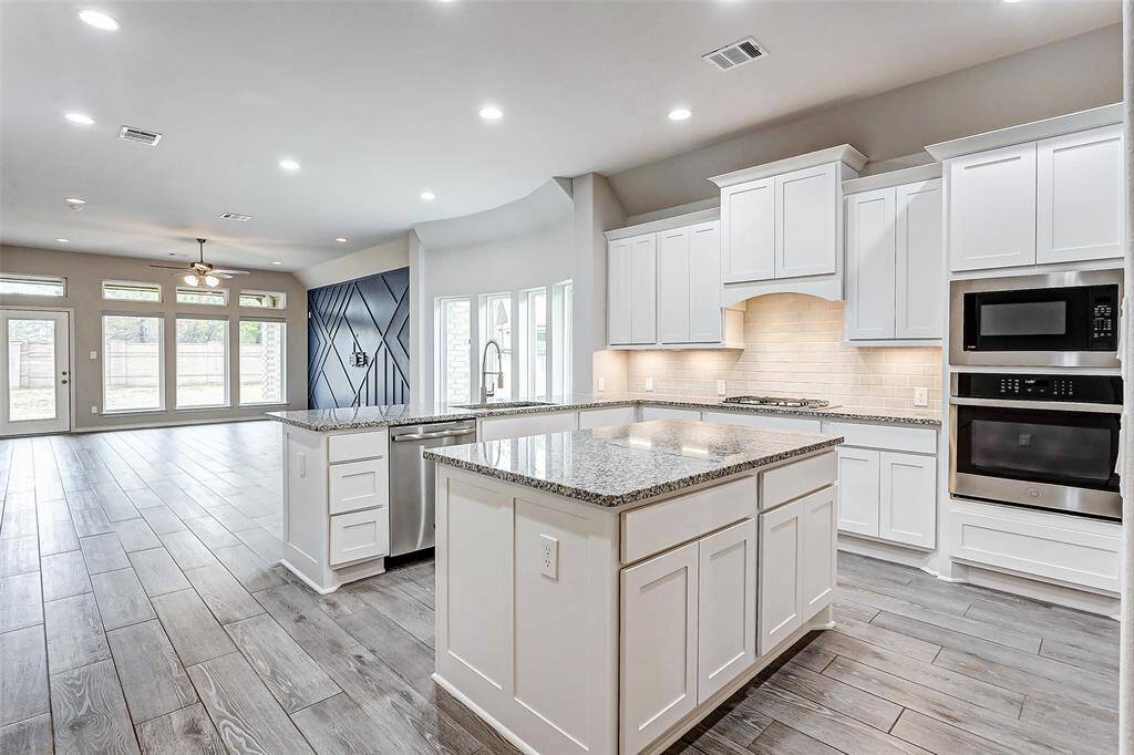 Alternative view of open layout, extending into a bright living area with expansive windows and wood-look flooring.