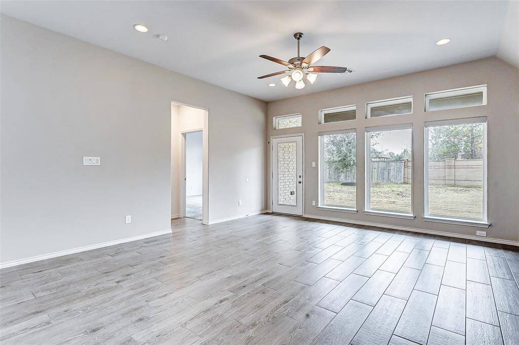 This spacious living room view leads to a fenced backyard, offering a seamless indoor-outdoor connection.