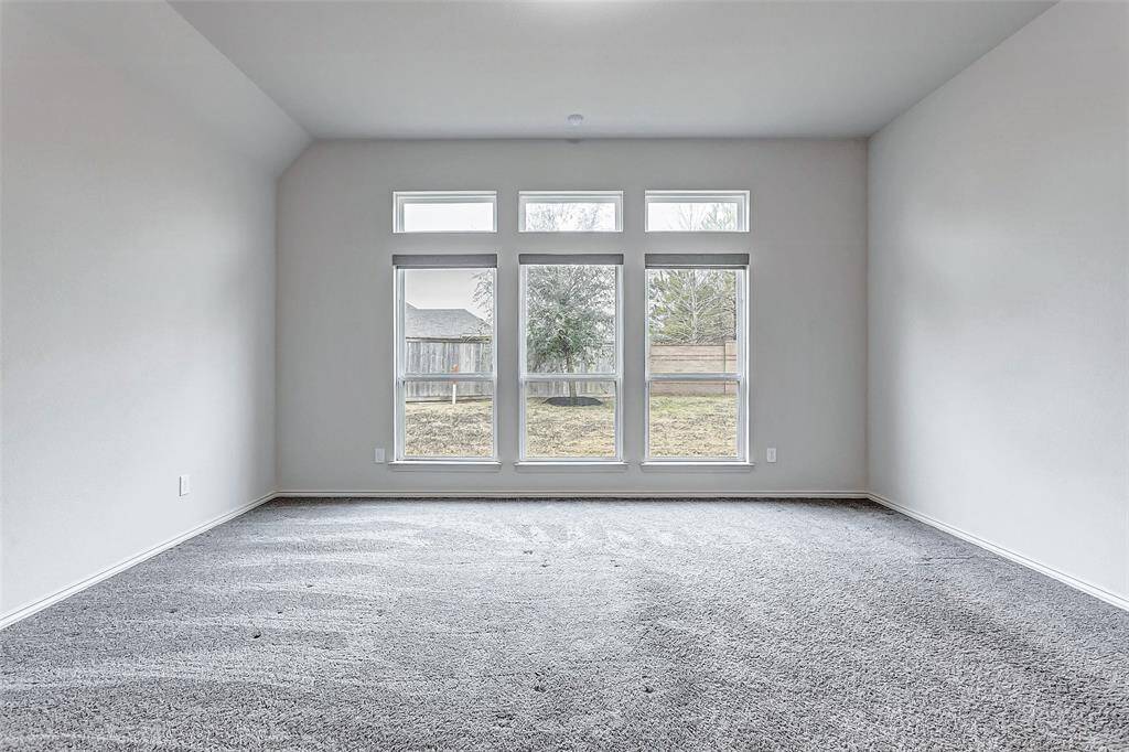 Bright, spacious room with large windows providing plenty of natural light. Fresh carpet and neutral walls create a welcoming atmosphere, ideal for a seating area near the windows.