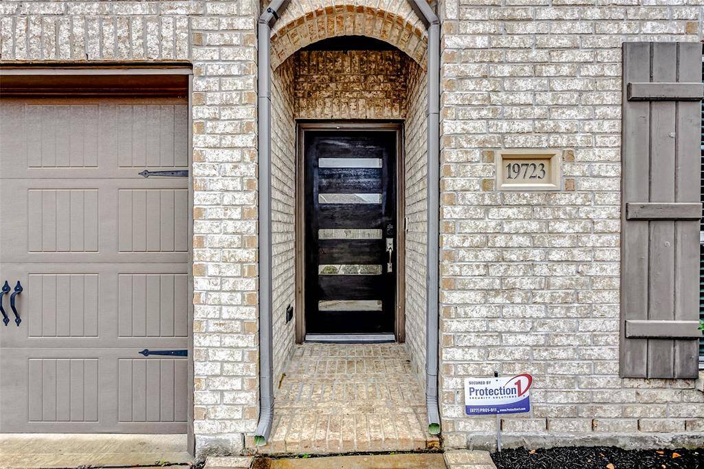 The entrance features a modern black door and light brick exterior offering a welcoming approach.