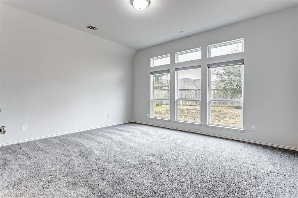 Large windows offering plenty of natural light and a view of the backyard. The neutral carpet and walls provide a versatile backdrop for any decor style.